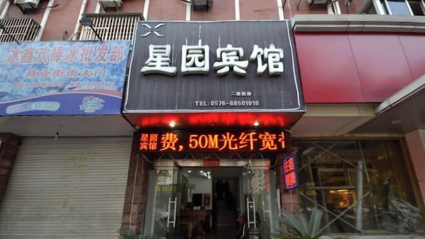 A hotel entrance with a signboard displaying the name and contact information. - Xingyuan Hotel (Taizhou)