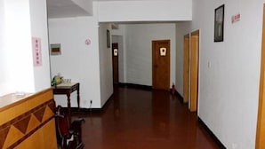 A hotel hallway with wooden doors, a reception desk, and a fire extinguisher. - Xingyuan Hotel (Taizhou)