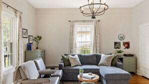 Ein Wohnzimmer mit einer Eckcouch, einem runden Couchtisch und einer Deckenleuchte.