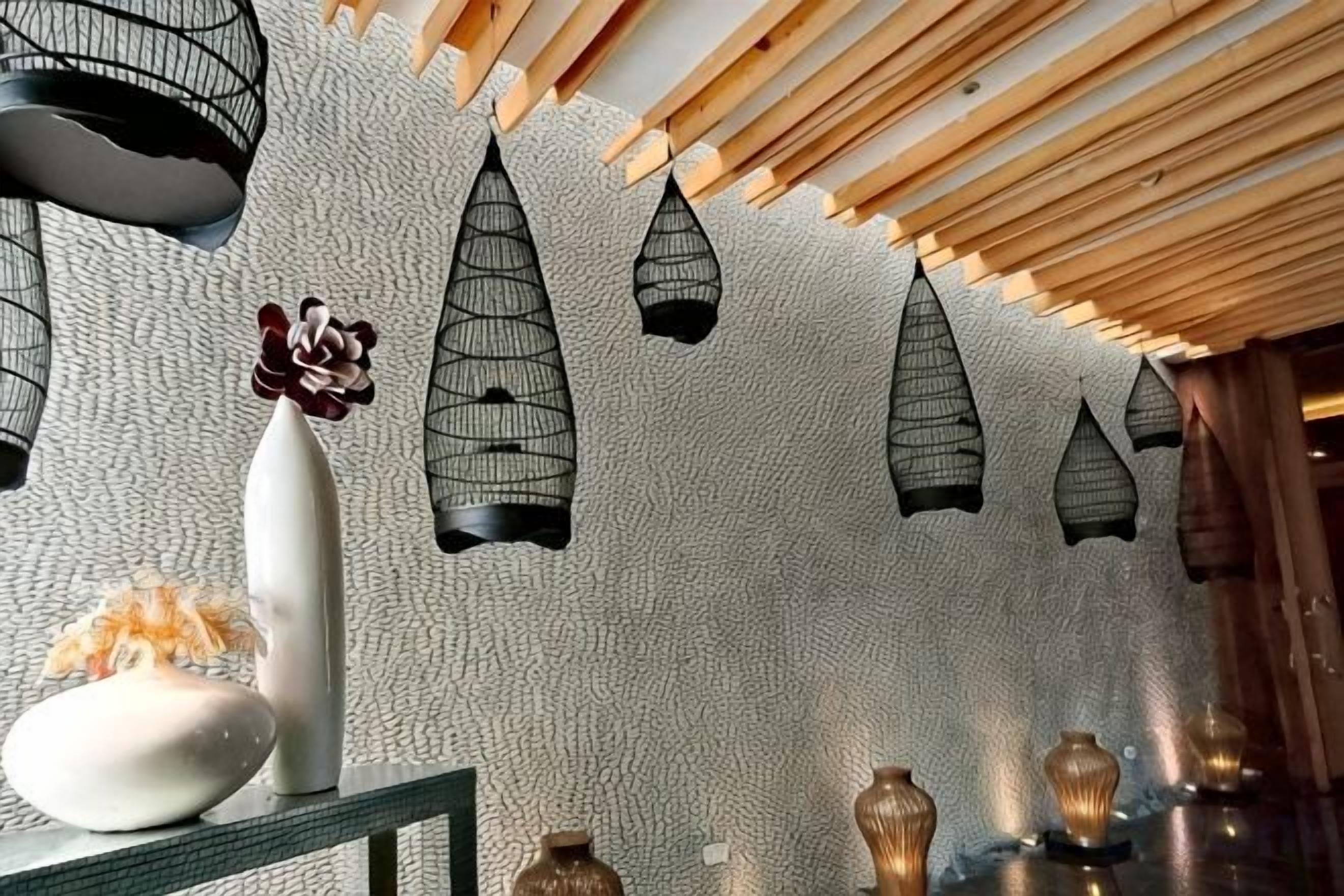 A room with a textured wall, hanging black lanterns, and a table with decorative items.