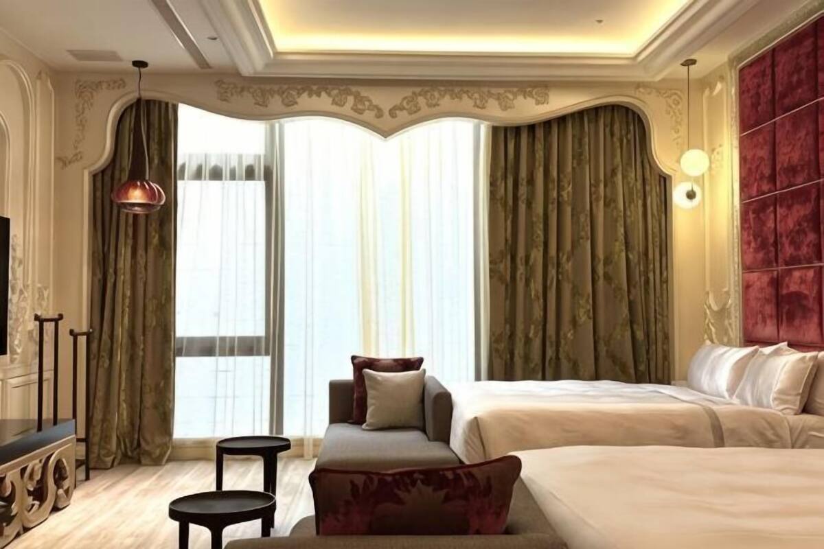 A hotel room with a large bed, a sofa, a small table, and a TV.