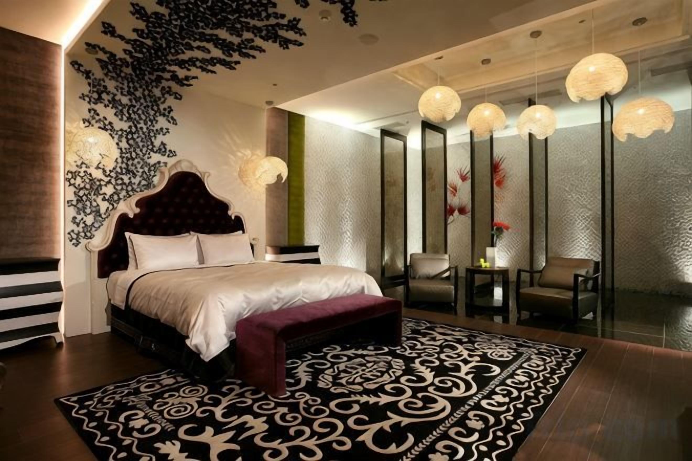 A modern bedroom with a large bed, a patterned rug, and a glass partition wall.