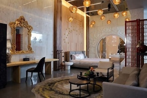 A modern hotel room with a bed, seating area, and a large mirror.