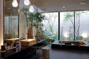 Un bagno moderno con un grande specchio, un mobile bagno in legno e piante in vaso.