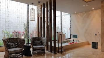 A modern interior with two wicker chairs, a tall column, and a tiled floor.
