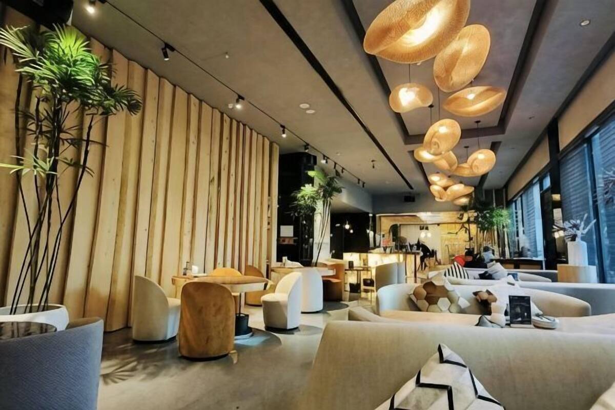 A modern interior with seating areas, a wooden wall, and hanging lights.