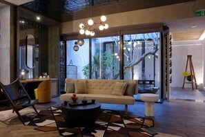 A modern interior with a sofa, a coffee table, a chair, and a large window with a view of trees.