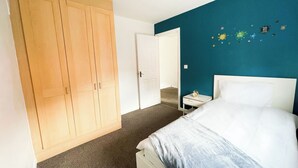 Een slaapkamer met een bed, een kledingkast, een nachtkastje en een wand versierd met sterren.