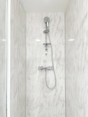 Eine moderne Dusche mit Handbrause und fest installiertem Wasserhahn.