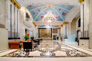 A grand lobby with a high ceiling, ornate chandelier, and a patterned floor. - Vienna International Hotel (Changsha)
