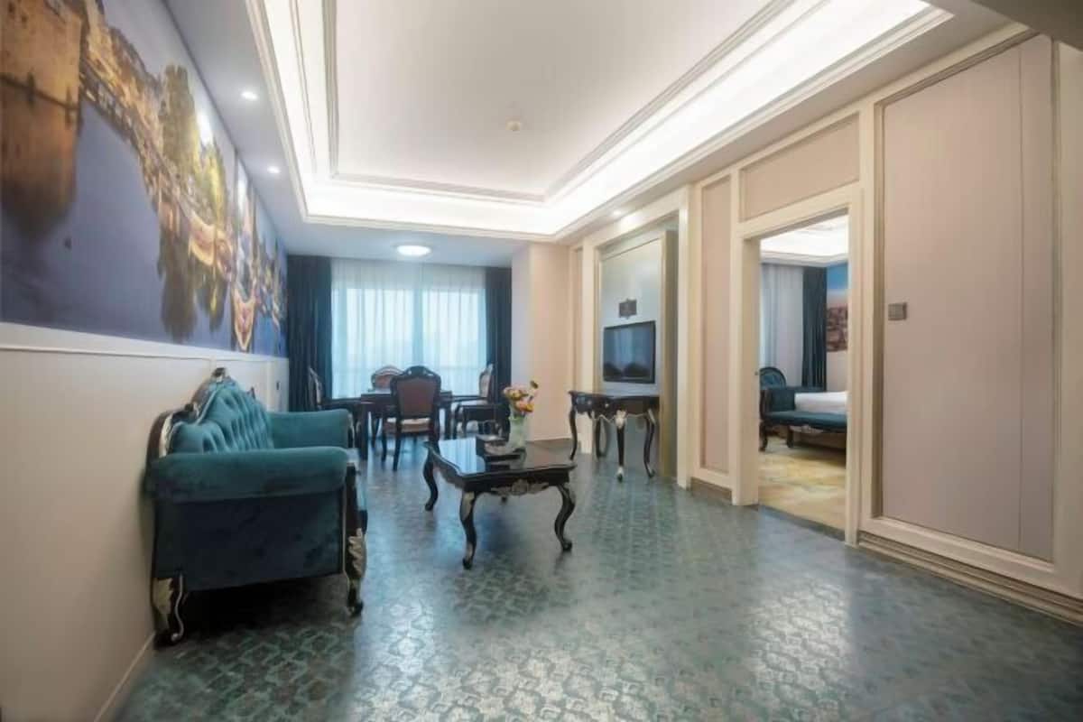 A hotel room with a living area, a dining table, and a TV.