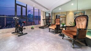 A spacious room with a large window offering a city view, a treadmill, and two upholstered chairs. - Vienna International Hotel (Changsha)