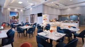 A modern dining area with tables and chairs, a kitchen counter, and a mural on the wall. - Vienna International Hotel (Changsha)