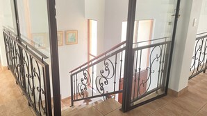 Un escalier avec une rampe en fer forgé et une porte en verre donnant sur une autre pièce.