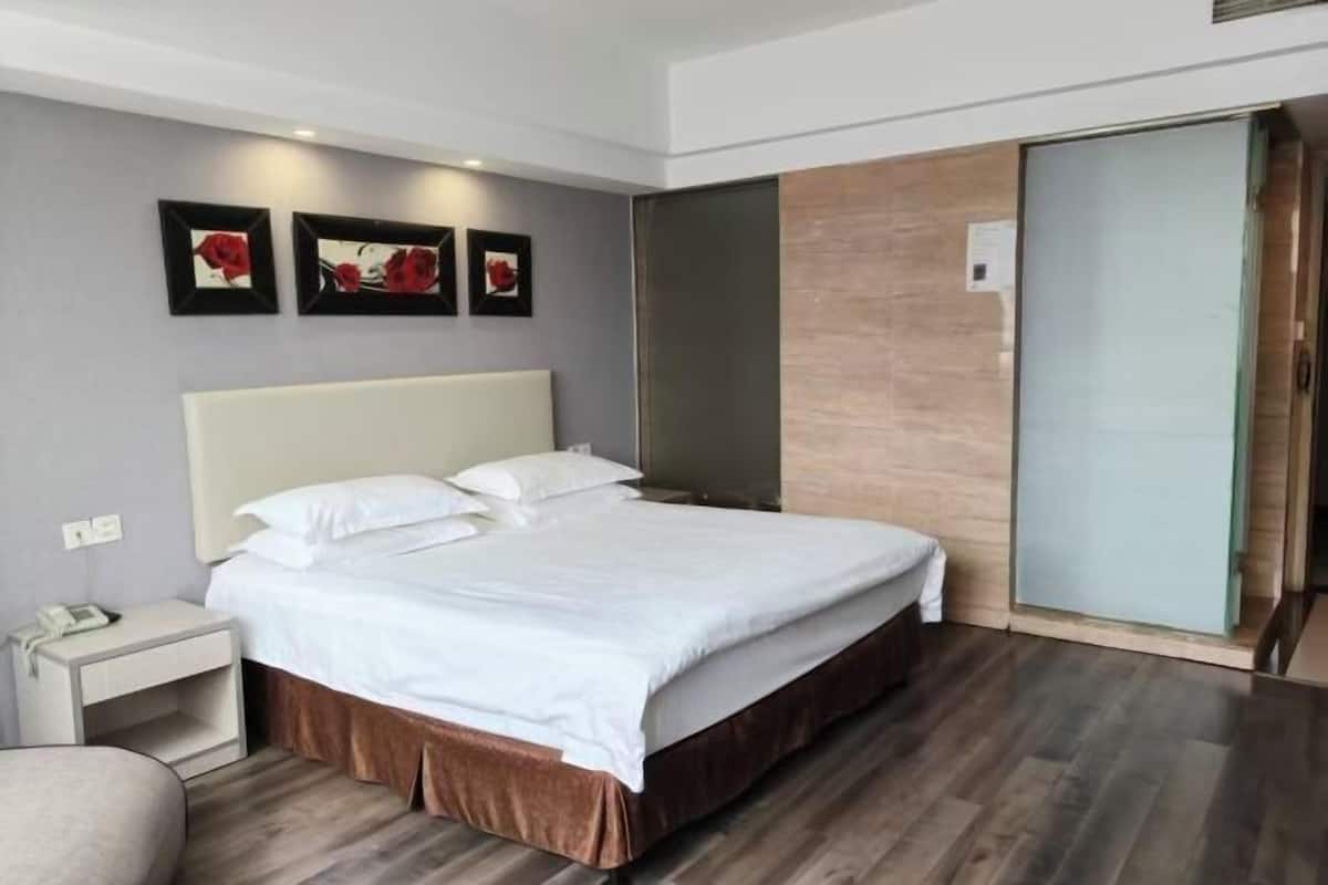 A modern hotel room with a large bed, a bedside table, and a wardrobe.