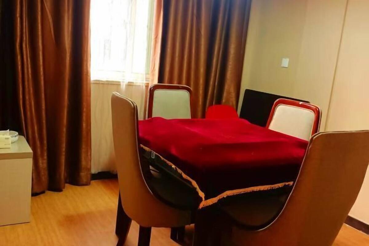 A small room with a single bed, a bedside table, and a window with curtains.