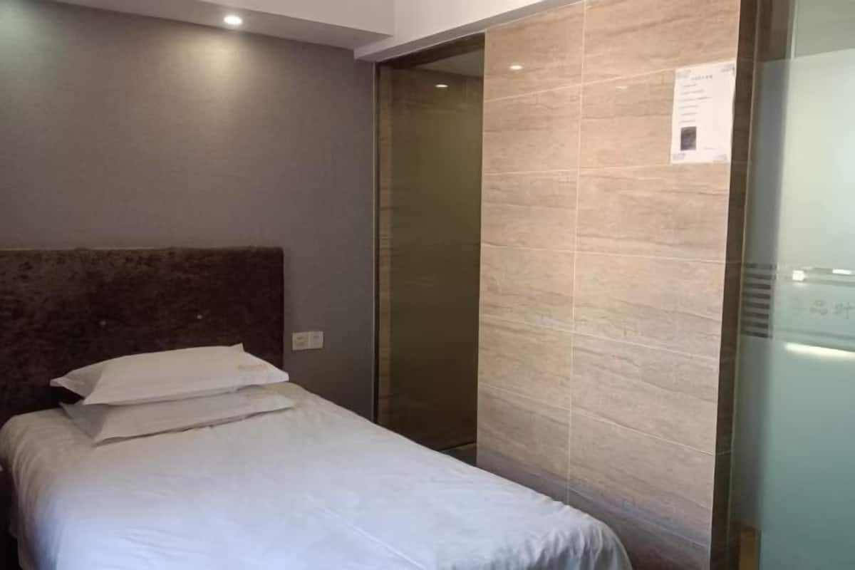 A hotel room with a bed, a headboard, a door, and a wall with a textured pattern.