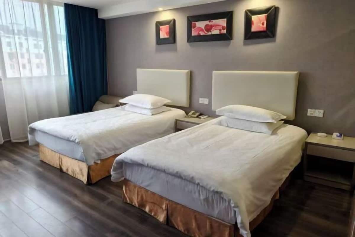 A hotel room with two beds, a desk, and a chair.
