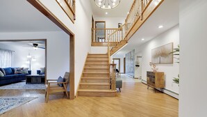 Un vaste espace de vie agrémenté d’un escalier en bois, d’un canapé bleu et d’une armoire en bois.