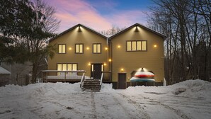 Une maison à deux étages, avec une façade en bois, un porche à l’avant et un escalier menant à l’entrée.
