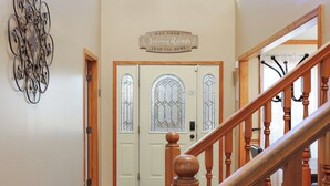 Un escalier en bois avec une rampe, un banc et une porte dotée d’une vitre en verre dépoli.