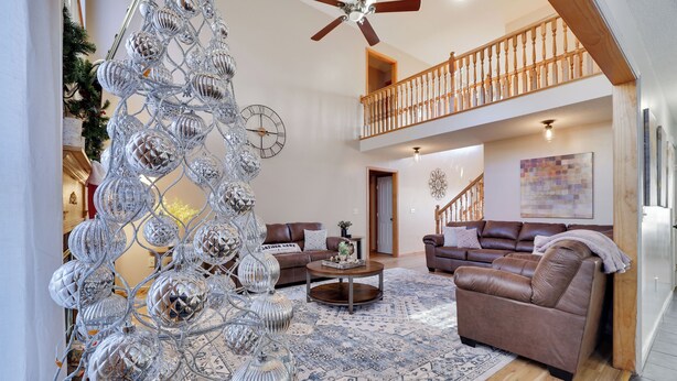 Un vaste salon doté d’un haut plafond, d’un grand lustre et d’un escalier menant à un étage supérieur.