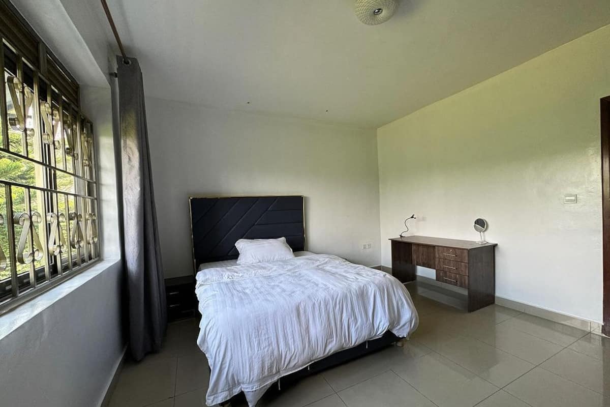 A bedroom with a bed, a bedside table, and a window with metal bars.