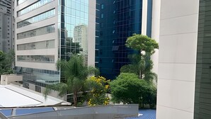 Un edificio moderno con ventanas de vidrio reflectante, rodeado de vegetación y un cielo despejado.