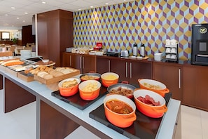 Ein reichhaltiges Buffet mit verschiedenen Speisen und einer Wand mit Muster im Hintergrund.