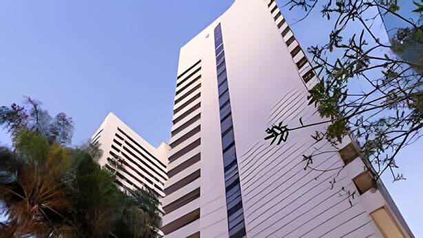 Un hotel moderno con una entrada destacada, ventanas amplias y una bandera visible.