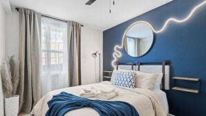 A bedroom with a bed, a bedside table, a mirror, and a wall-mounted shelf. - Spacious 6-bedroom house in beautiful Downtown Brevard (Brevard)