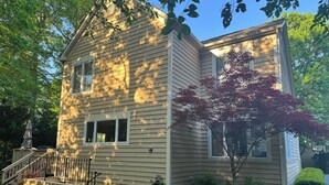 A two-story house with a front porch, a small staircase, and a garden with chairs and a tree. - Clean comfy Reston B&B with ping pong table (Reston)