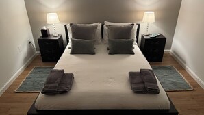 A neatly made bed with two pillows, two bedside tables with lamps, and two folded towels on the bed. - Clean comfy Reston B&B with ping pong table (Reston)