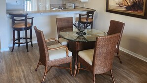 Un comedor con sillas de mimbre, una mesa de vidrio y una lámpara colgante.