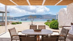 An outdoor dining area with a view of the sea and mountains. - Donum Dei Seaside Suites & Villa (Paros)