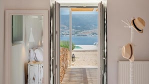 A doorway leading to a balcony with a view of the sea and mountains. - Donum Dei Seaside Suites & Villa (Paros)
