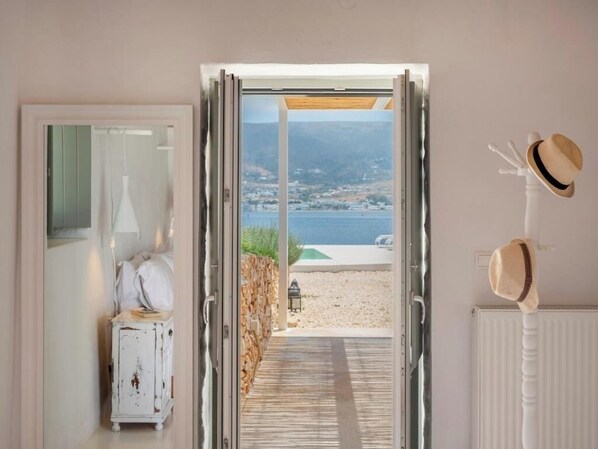 A doorway leading to a balcony with a view of the sea and mountains. - Donum Dei Seaside Suites & Villa (Paros)