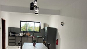 A spacious kitchen with a dining area, a window, and a modern chandelier. - Space Villa 3 (Grand Baie)