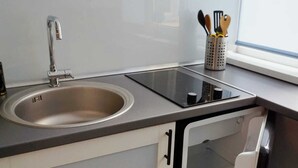 Et lille køkken med vask, komfur og et minikøleskab.