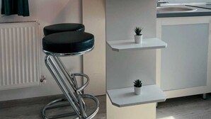Et moderne køkken med en barstol, en lille potteplante og et vinglas på bordet.