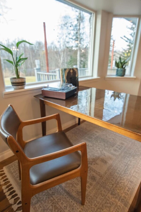 A wooden chair with a cushioned seat and backrest, positioned in front of a glass table.