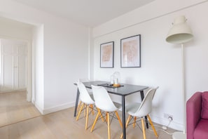 A dining area with a table, chairs, and two framed calligraphy pieces on the wall.
