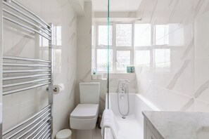 A modern bathroom with a glass shower enclosure, a toilet, and a bathtub.