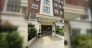 A building entrance with a double door, a small garden area, and a pathway leading to the entrance.
