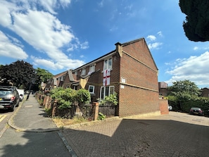 A two-story brick building with a flat roof and a small front porch. - Charming 2BD Canal-Side Home in East London (London)