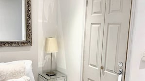 A bedroom with a bed, a bedside table with a lamp, a mirror, and a double door. - Lovely one bedroom flat (Wooburn Green, Bourne End)