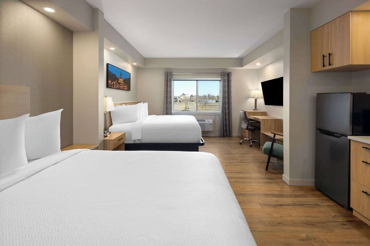 Een hotelkamer met twee bedden, een bureau, een televisie en een koelkast.
