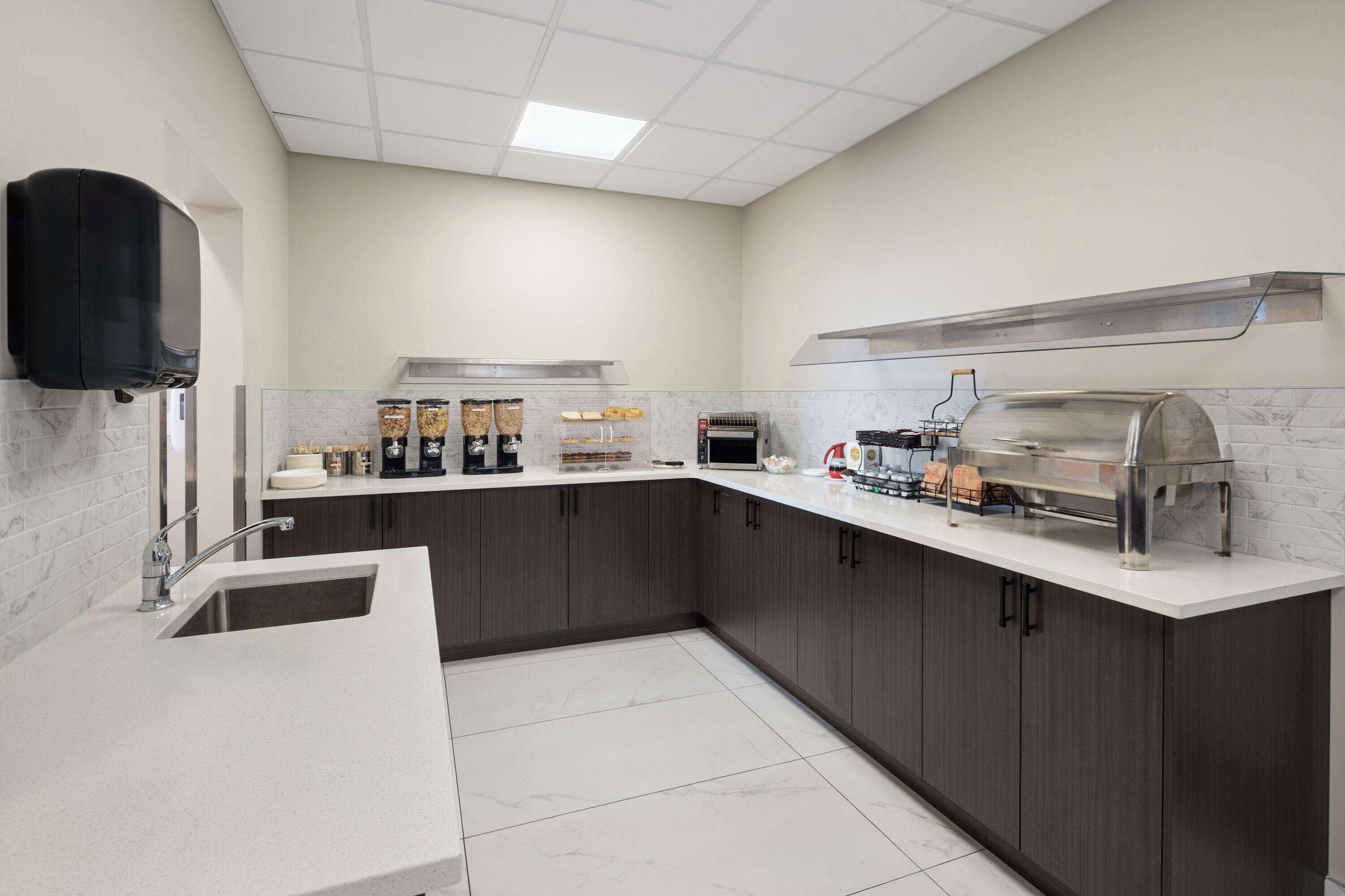 Een moderne keuken met een marmeren aanrecht, een inbouwgootsteen, een koffiehoek en een rvs afzuigkap.