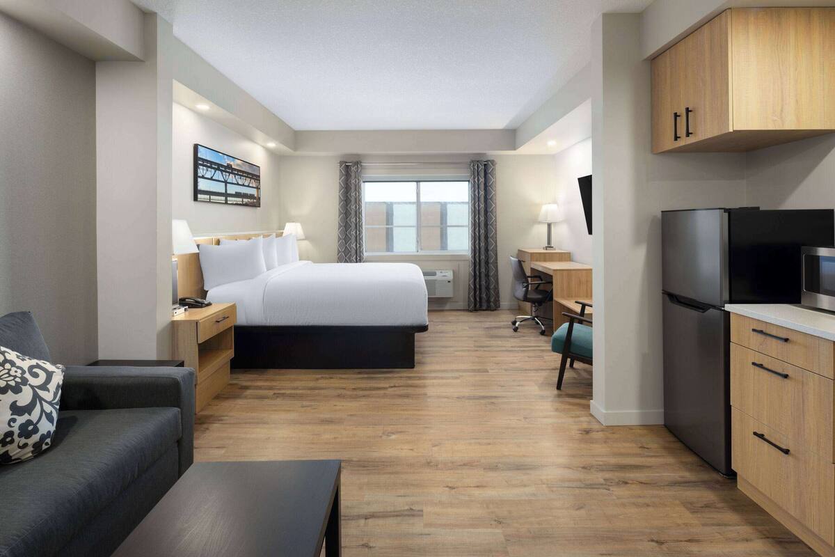 Een hotelkamer met een bed, een bureau, een televisie, een koelkast en een bank.