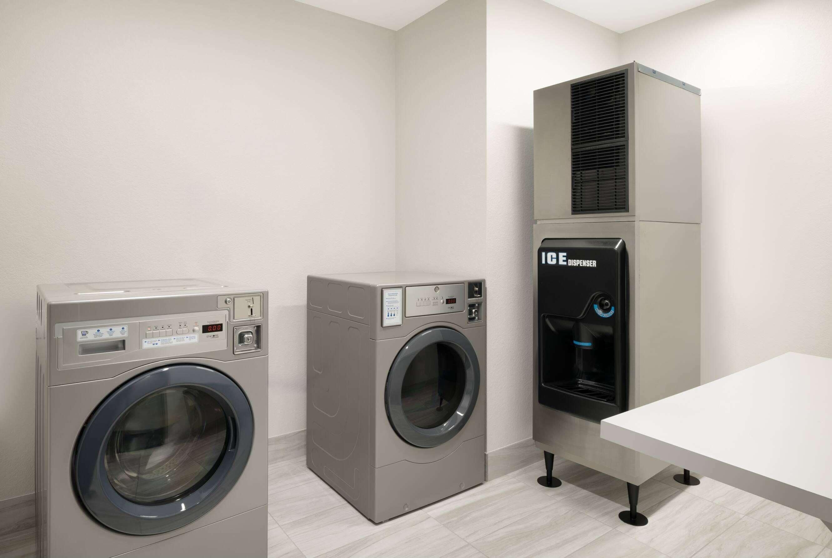 A laundry room with two front-loading washing machines and a water dispenser.